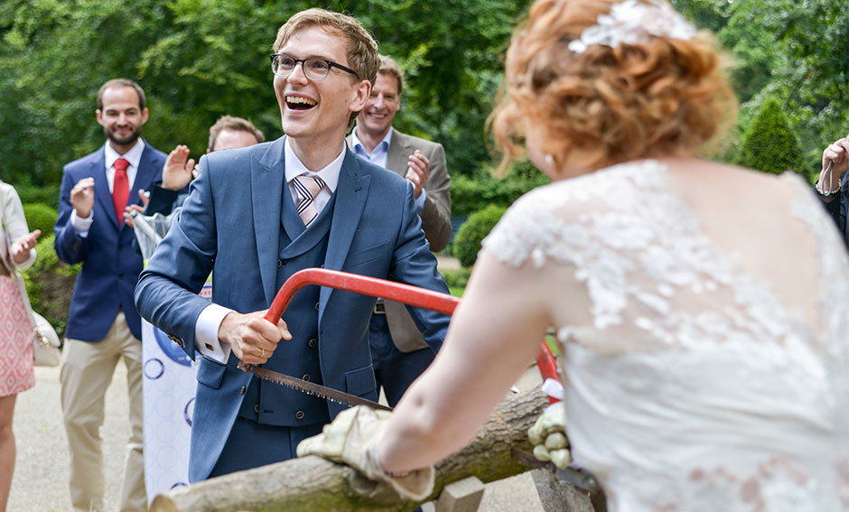 Hochzeitsfoto Hochzeitsspiele Tradition Holzstamm sägen Brautpaar Freude Hochzeitsfeier Berlin